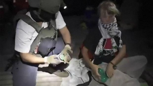 This video grab taken from a handout footage released by the Israeli Foreign Ministry on October 1, 2025  shows an Israeli soldier with Swedish climate activist Greta Thunberg (R) after several vessels of the Global Sumud Flotilla 