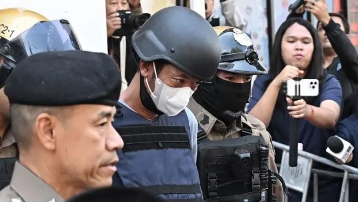 Thai national Ekkalak Paenoi (C), a suspect in the alleged killing of former lawmaker of the dissolved Cambodia National Rescue Party Lim Kimya, is escorted into a police van to transport him to the Criminal Court from Chana Songkram Police Station in Bangkok on January 13, 2025. (AFP/FILE PHOTO)
