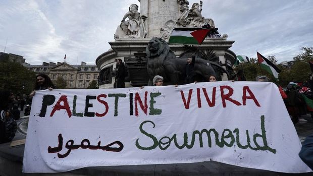 Pro-Palestinian demonstrators march behind a banner 