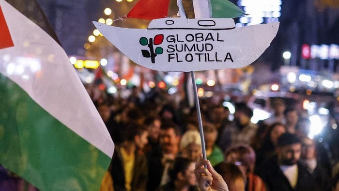 Pro-Palestinian demonstrators march behind a banner 