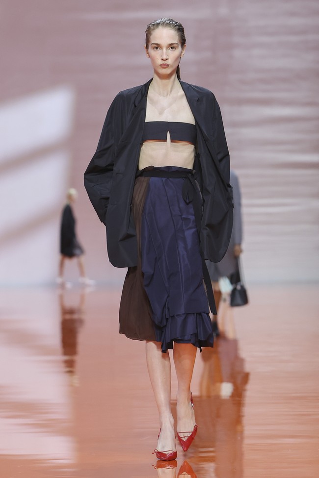 Koleksi ini juga menunjukkan kebebasan dalam memadukan hierarki pakaian. Seragam khas Prada dapat berdiri sejajar dengan gaun malam, sementara elemen feminin dipadukan secara tak terduga, membentuk definisi baru tentang elegansi. (Foto: Dok. Prada)