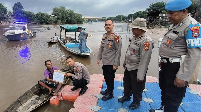 Polisi menyapa nelayan di Sungai Siak, Pekanbaru lewat program Jalur, Jumat (3/10/2025). Tak hanya membagikan sembako, polisi juga bergotong-royong membersihkan kampah di sepanjang Sungai Siak.
