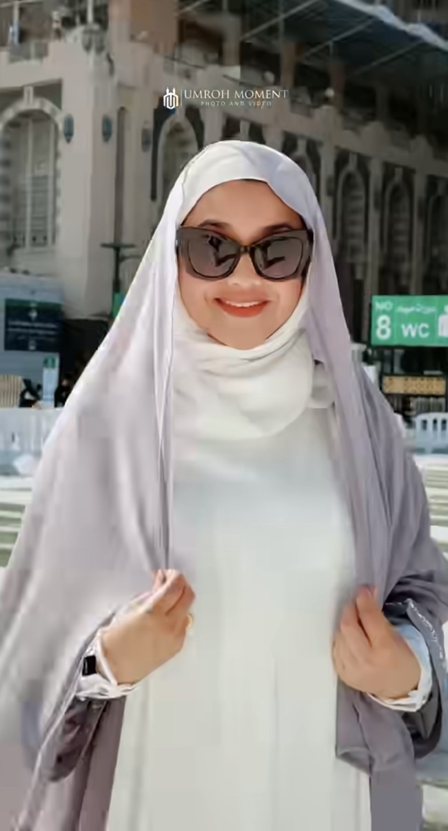 Sarah tampil dengan gamis polos longgar yang memberi kesan bersih dan anggun. Di bagian luarnya ia menambahkan jilbab panjang berwarna abu-ungu lembut yang menambah kesan syar’i. Foto: Instagram/@sazarita