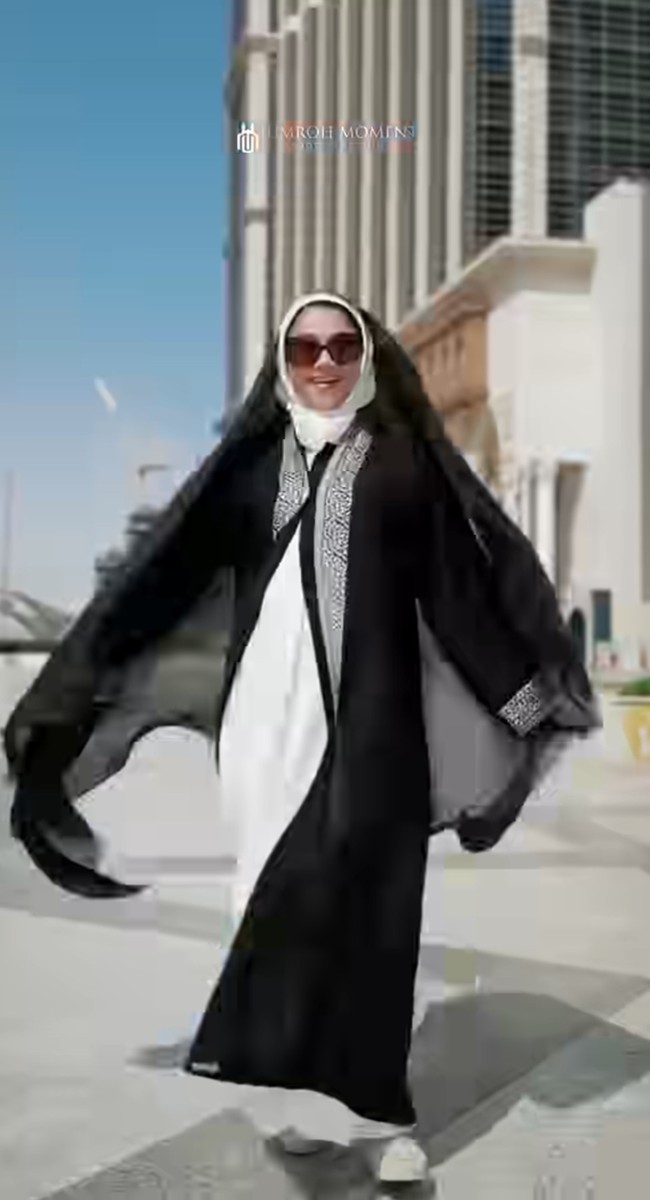 Di momen berbeda Sarah mengenakan gamis putih polos sebagai inner utama, memberi kesan bersih dan elegan. Bagian luar dilapisi dengan abaya hitam panjang yang menjuntai, memberikan kontras tegas dengan gamis putih di dalamnya. Foto: Instagram/@sazarita