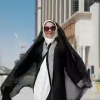 Di momen berbeda Sarah mengenakan gamis putih polos sebagai inner utama, memberi kesan bersih dan elegan. Bagian luar dilapisi dengan abaya hitam panjang yang menjuntai, memberikan kontras tegas dengan gamis putih di dalamnya. Foto: Instagram/@sazarita