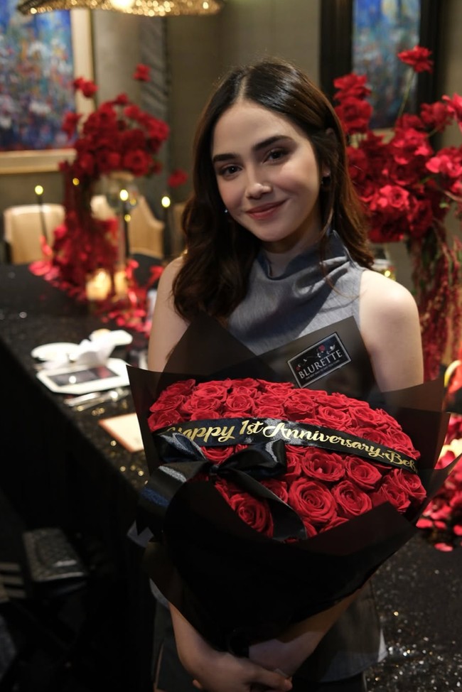 Syifa tampil cantik dalam balutan busana tanpa lengan berwarna abu-abu. Dalam foto terlihat dirinya yang memegang buket bunga mawar merah pemberian El. Foto: Instagram/@syifahadju