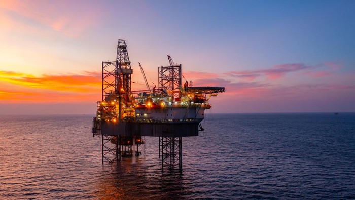 Aerial view of silhouette offshore jack up drilling rig during sunset - oil and gas industry