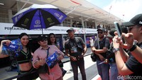 Penggemar berfoto bersama umbrella girl saat pit lane walk MotoGP Indonesia 2025.