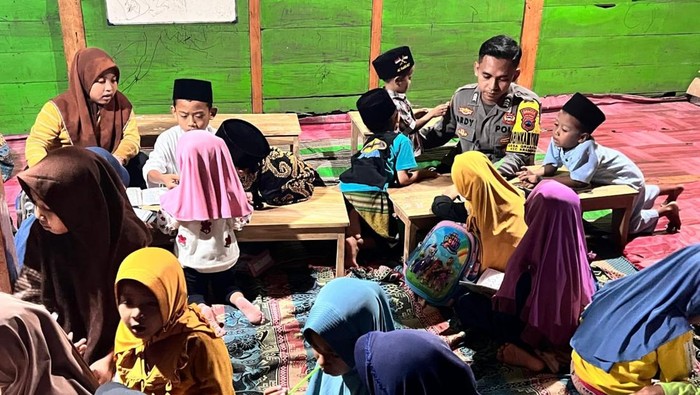 Bhabinkamtibmas Polsek Kradenan, Brigadir Ardy Teguh, saat memberikan Al-Quran hingga buku kepada anak-anak yang mengaji di Desa Grabagan, Kecamatan Kradenan, Kabupaten Grobogan, Sabtu (4/10/2025).
