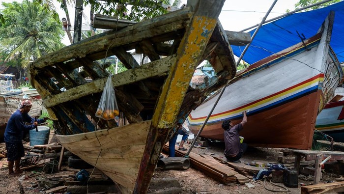 Pekerja menyelesaikan perbaikan perahu nelayan di Desa Karang Serang, Kabupaten Tangerang, Banten, Selasa (30/9/2025). Menurut pekerja jasa perbaikan perahu berupa pengecatan, penambalan hingga penggantian kayu  tersebut berkisar Rp15 juta - Rp30 juta per unitnya tergantung jenis kerusakan dan ukuran perahu. ANTARA FOTO/Putra M. Akbar/rwa.