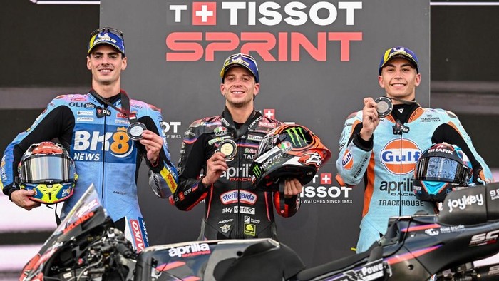 Winner Aprilia Racing teams Italian MotoGP rider Marco Bezzecchi (C), second-placed BK8 Gresini Racing MotoGP teams Spanish MotoGP rider Fermin Aldeguer (L) and third-placed Trackhouse MotoGP Teams Spanish rider Raul Fernandez celebrate on the podium after the Sprint Race at the MotoGP Indonesian Grand Prix at the Mandalika International Circuit in Mandalika, West Nusa Tenggara on October 4, 2025. (Photo by SONNY TUMBELAKA / AFP)
