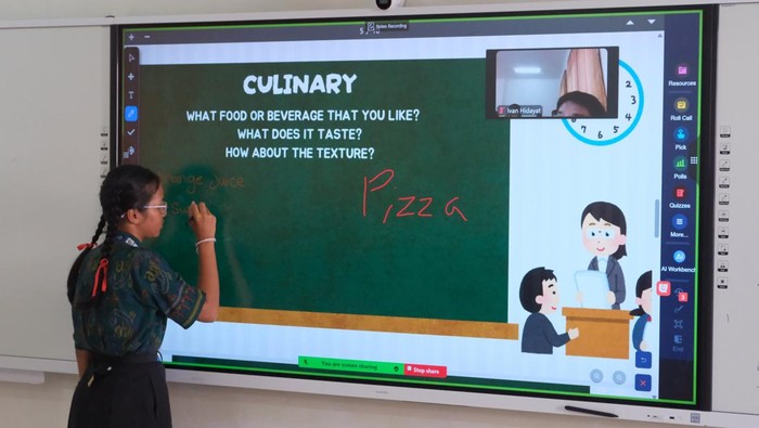 Seorang guru memberikan penjelasan kepada siswa yang mengikuti pelajaran bahasa inggris dengan metode pembelajaran smart classroom atau ruang kelas pintar di SMP Negeri 15 Denpasar, Bali, Jumat (3/10/2025). Kegiatan tersebut merupakan bagian dari peluncuran teknologi Wi-Fi 7 dengan kecepatan hingga 2 Gbps sekaligus penerapan smart classroom atau ruang kelas pintar yakni metode pembelajaran modern yang mengintegrasikan teknologi digital dan konektivitas internet serta dapat melakukan kolaborasi belajar virtual antar sekolah. ANTARA FOTO/Nyoman Hendra Wibowo/YU