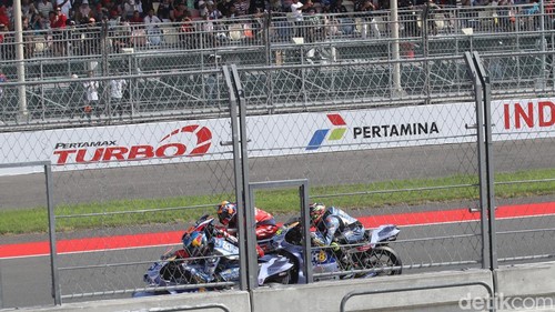Suasana MotoGP Indonesia 2025 di Sirkuit Internasional Pertamina Mandalika, Lombok Tengah, Nusa Tenggara Barat, Minggu (5/10/2025), berlangsung penuh adrenalin dan sorak sorai penonton. Para pembalap saling bersaing ketat, memacu kecepatan maksimal di lintasan sepanjang sirkuit yang menantang.