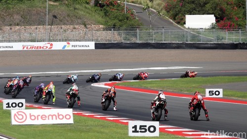 Suasana MotoGP Indonesia 2025 di Sirkuit Internasional Pertamina Mandalika, Lombok Tengah, Nusa Tenggara Barat, Minggu (5/10/2025), berlangsung penuh adrenalin dan sorak sorai penonton. Para pembalap saling bersaing ketat, memacu kecepatan maksimal di lintasan sepanjang sirkuit yang menantang.