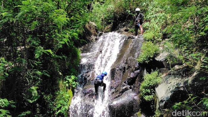 Salah satu peserta canyoning menuruni tebing dengan dipandu oleh tim