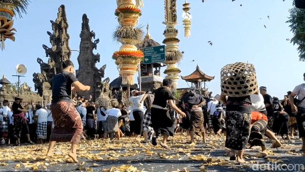Keseruan warga dan bule-bule berbaur melemparkan ketupat ke udara saat tradisi Aci Tabuh Rah Pengangon, di Desa Kapal, Badung, Senin (6/10/2025). (Agus Eka)