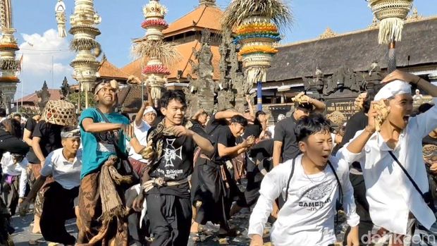 Keseruan warga dan bule-bule berbaur melemparkan ketupat ke udara saat tradisi Aci Tabuh Rah Pengangon, di Desa Kapal, Badung, Senin (6/10/2025). (Agus Eka)