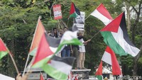 Bendera Indonesia dan Palestina berkibar berdampingan di tengah kerumunan massa. Simbol solidaritas dua bangsa yang menyerukan perdamaian dan keadilan bagi Palestina.