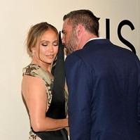 Ben Affleck terlihat mencondongkan tubuhnya untuk berbicara di telinga Jennifer Lopez, sementara sang aktris membalas dengan senyum lembut. Foto: Getty Images/Slaven Vlasic