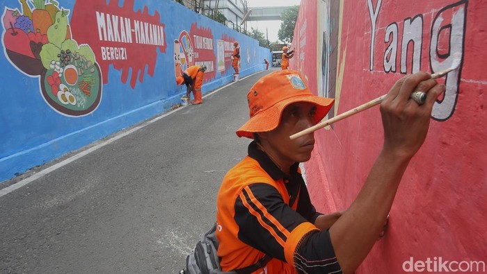 Petugas Penanganan Prasarana dan Sarana Umum (PPSU) melukis mural terkait kampanye hidup sehat di Cikoko, Pancoran, Jakarta Selatan, Selasa (7/10/2025). Sejumlah pesan dengan ilustrasi besar berlatar warna merah membentang di dinding sebuah gang. Pesan hidup sehat itu seperti 'Olahraga Secara Teratur', 'Membuka Jendela dan Pintu Tiap Hari', 'Tidak Merokok dan Minum-minuman Keras' dan 'Memperbaiki Saluran dan Talang Air yang Tidak Lancar'.