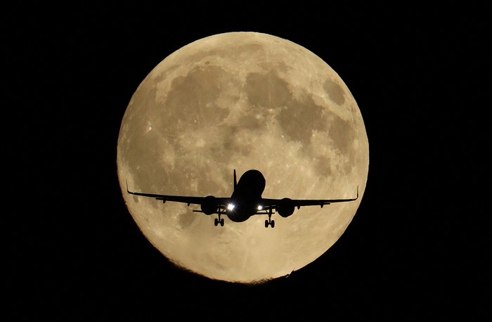 A passenger plane passes in front of the first supermoon of the year, known as the Harvest Moon, as it flies above London, Britain, October 6, 2025. REUTERS/Toby Melville     TPX IMAGES OF THE DAY