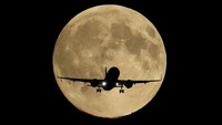 A passenger plane passes in front of the first supermoon of the year, known as the Harvest Moon, as it flies above London, Britain, October 6, 2025. REUTERS/Toby Melville     TPX IMAGES OF THE DAY