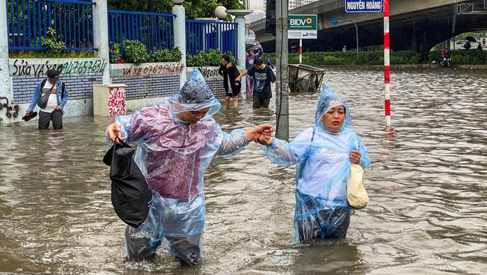 Hujan deras akibat Topan Matmo melanda Hanoi, Vietnam, Selasa (7/10/2025), menyebabkan banjir meluas di jalan-jalan utama dan mengganggu aktivitas warga. Banyak kendaraan terjebak di genangan air, sementara pejalan kaki harus mengarungi jalan setinggi lutut dan terkadang menggendong hewan peliharaan mereka untuk keselamatan. REUTERS/Thinh Tien Nguyen