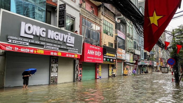 Hujan deras akibat Topan Matmo melanda Hanoi, Vietnam, Selasa (7/10/2025), menyebabkan banjir meluas di jalan-jalan utama dan mengganggu aktivitas warga. Banyak kendaraan terjebak di genangan air, sementara pejalan kaki harus mengarungi jalan setinggi lutut dan terkadang menggendong hewan peliharaan mereka untuk keselamatan. REUTERS/Thinh Tien Nguyen