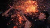 Para pemuda yang ikut serta mengenakan kain kamen dan saput khas Bali, dengan tubuh yang hanya berbalut kain tradisional, berlari di tengah gelapnya malam sambil saling memukul bara api yang menyala. Percikan api beterbangan, menciptakan pemandangan dramatis yang memikat perhatian warga dan wisatawan. ANTARA FOTO/Nyoman Hendra Wibowo