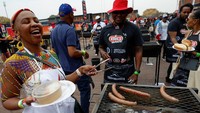 Asap panggangan mengepul di tengah sorak gembira warga. Braai massal ini tidak hanya menjadi ajang kebersamaan, tetapi juga bentuk solidaritas untuk mengakhiri kelaparan di Afrika Selatan. Foto: Reuters/Luc Gnago