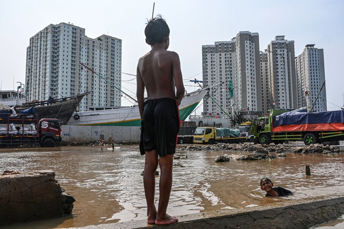 Seorang anak mengamati proses bongkar muat sepeda motor saat banjir rob di Pelabuhan Sunda Kelapa, Jakarta, Rabu (8/10/2025). Badan Penanggulangan Bencana Daerah (BPBD) Jakarta mengimbau warga pesisir utara untuk mewaspadai potensi banjir rob pada 8-15 Oktober 2025 yang disebabkan fenomena pasang maksimum air laut bersamaan dengan fase Bulan Purnama. ANTARA FOTO/Sulthony Hasanuddin/rwa.