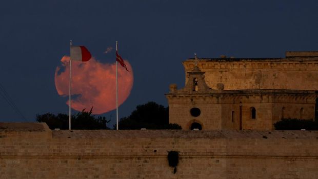 Supermoon pertama tahun ini, yang dikenal sebagai Harvest Moon, terbit di atas Benteng Saint Angelo di Grand Harbour, seperti yang terlihat dari Floriana, Malta, 7 Oktober 2025. (REUTERS/Darrin Zammit Lupi)