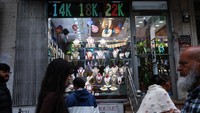 Sejumlah pejalan kaki melintas di depan layar digital bertema emas di kawasan Jackson Heights, Queens, New York City, Rabu (8/10/2025). Lonjakan harga emas di atas US$ 4.000 per troy ons mencerminkan meningkatnya minat investor terhadap aset lindung nilai. REUTERS/Shannon Stapleton  