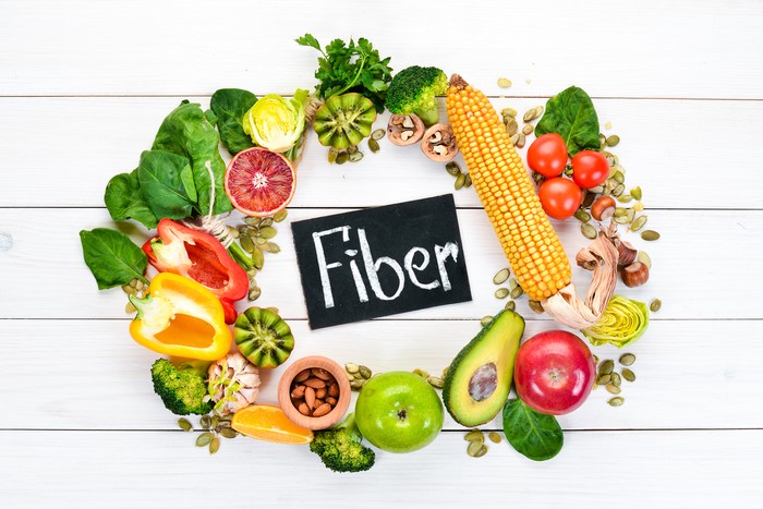 Foods containing natural fiber: avocados, kiwi, apple, tomatoes, spinach, paprika, orange, lemon. Top view. Free space for your text. On a white background.