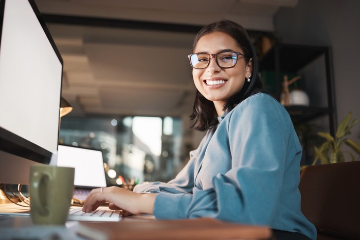 Space, computer and portrait of woman in office at night, working and research idea with mockup screen. Mock up, happy and businesswoman search online for creative design, inspiration and ppt review