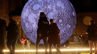 Warga melintas di depan instalasi bulan raksasa tiup di pusat kota Berlin saat Festival of Lights, Rabu (8/10/2025). Instalasi kreatif menjadi daya tarik baru dalam festival yang merayakan imajinasi dan kebersamaan. REUTERS/Fabrizio Bensch 
