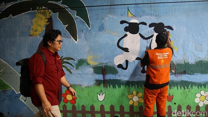 Mural Hijau Hiasi Tanah Abang Jakpus Petugas Penanganan Prasarana dan Sarana Umum (PPSU) Kelurahan Gelora, Tanah Abang melukis mural bertema 'Hijau' di kolong Gatot Subroto, Jakarta Pusat, Kamis (9/10/2025). Sejumlah pesan visual terlihat dari landscape peternakan sapi dan domba. Tampak dua karakter domba menyerupai karakter dalam film animasi Shaun the Sheep.