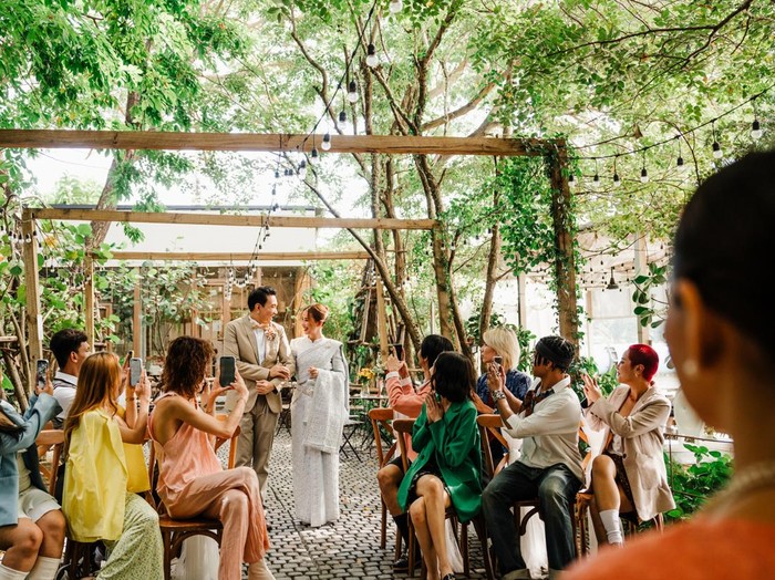 A joyful Thai wedding ceremony featuring the bride, father, and guests in a serene outdoor setting. Rustic charm, greenery, and cultural traditions create a vibrant celebration.