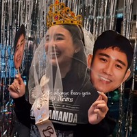 Amanda juga mengenakan selempang pink bertuliskan ‘Bride To Be’, bando bertuliskan ‘Bride’ serta veil di kepalanya. Di kedua tangannya wanita 25 tahun itu memegang kipas dengan foto wajah Kenny. Foto: Instagram