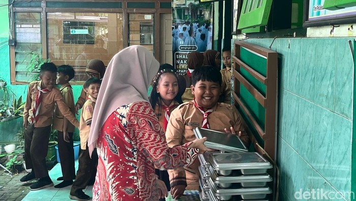 Guru SD Negeri Dinoyo saat membagikan menu MBG ke siswa hari ini