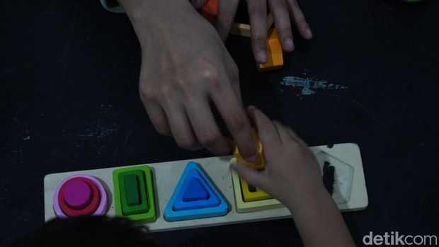 Momen tangan anak mengambil susunan mainan geometris yang disusun dengan warna dan bentuk yang senada