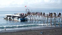 Penumpang yang akan berangkat ke Pulau Nusa Penida berjalan di dermaga Pelabuhan Tribuana, Desa Kusamba, Klungkung, Bali, Jumat (10/10/2025). Meski era modern telah menghadirkan kapal motor berukuran besar, warga masih mengandalkan perahu kayu ini karena dinilai efisien dan mampu menjangkau pantai-pantai kecil di pulau tujuan. ANTARA FOTO/Nyoman Hendra Wibowo