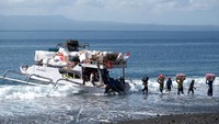 Sejumlah pekerja terlihat memindahkan berbagai barang ke dalam perahu tradisional yang bersandar di tepi pantai. Perahu tersebut menjadi alat transportasi utama warga untuk mengirim logistik ke kawasan wisata Pulau Nusa Penida. ANTARA FOTO/Nyoman Hendra Wibowo