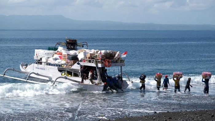Pekerja memindahkan berbagai barang ke dalam perahu tradisional di Pelabuhan Tribuana, Desa Kusamba, Klungkung, Bali, Jumat (10/10/2025). Perahu yang dapat mengangkut beban 15 ton tersebut merupakan alat transportasi laut tradisional yang digunakan oleh warga untuk sehari-hari mengirim logistik ke kawasan wisata di Pulau Nusa Penida. ANTARA FOTO/Nyoman Hendra Wibowo