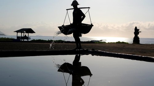 Petani menyiram air laut ke lahan saat proses produksi garam alami secara tradisional di Desa Kusamba, Klungkung, Bali, Jumat (10/10/2025). Menurut petani garam di desa tersebut pada bulan Oktober ini merupakan puncak masa panen garam dengan kondisi cuaca matahari yang bagus dan rata-rata setiap harinya memanen garam sebanyak 20 kg yang dijual seharga Rp10 ribu hingga Rp25 ribu per kg sesuai kualitas. ANTARA FOTO/Nyoman Hendra Wibowo