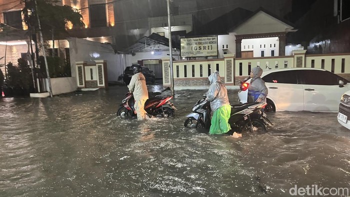 Pengendara sepeda motor mendorong kendaraannya yang mogok gegara banjir di Jalan Wahid Hasyim Medan
