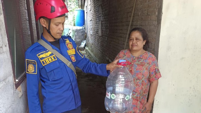 Petugas Damkar mengevakuasi ular kobra dengan dimasukkan ke galon air mineral.