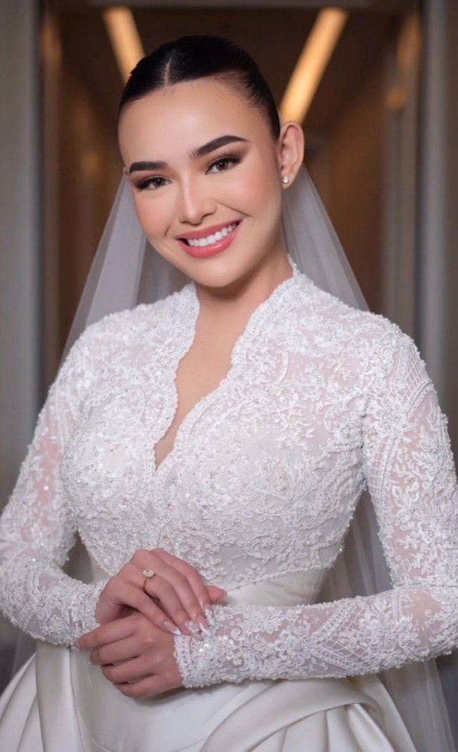 Arnold Dominggus menata rambut Amanda dengan gaya sanggul rendah berbelah tengah yang sleek dan rapi. Look ini menonjolkan fitur wajahnya yang tegas sekaligus mempertegas kesan anggun dalam balutan gaun lace putihnya. Foto: Instagram/@bennusorumba