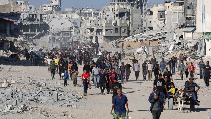 Palestinians walk among rubble following Israeli forces withdrawal from the area, amid a ceasefire between Israel and Hamas in Gaza, in Gaza City October 11, 2025. REUTERS/Ebrahim Hajjaj