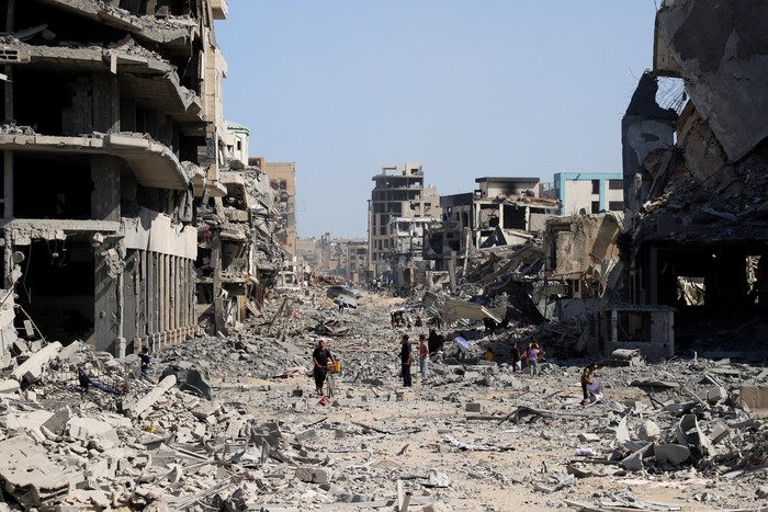 Palestinians walk among rubble following Israeli forces withdrawal from the area, amid a ceasefire between Israel and Hamas in Gaza, in Gaza City October 11, 2025. REUTERS/Ebrahim Hajjaj